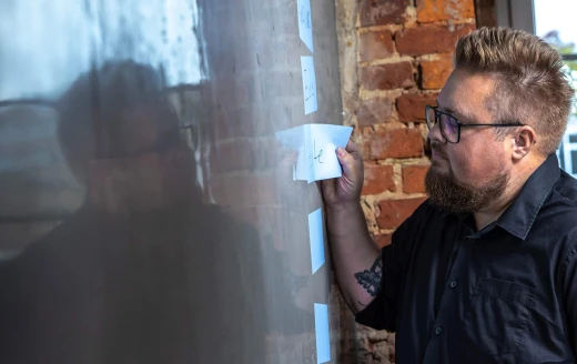 Klebezettel an einer Wand. René klebt Zettel an die.